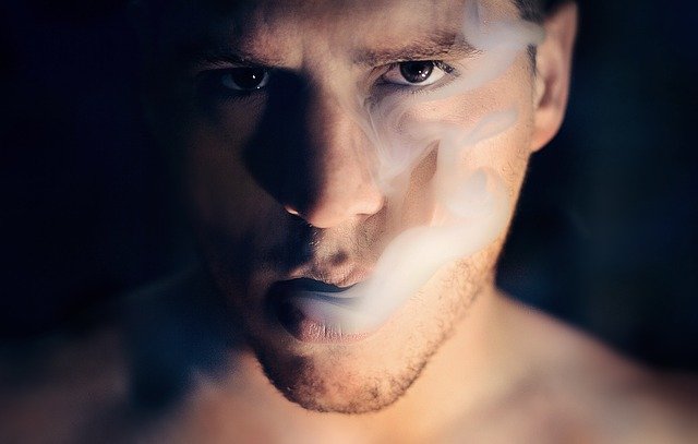 Mužovi ide z úst cigaretový dym