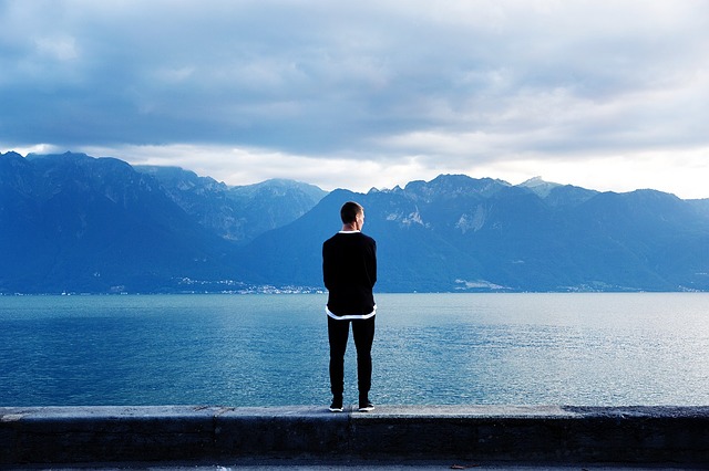 Mladý muž stojí pri jazere a pozerá sa do diaľky